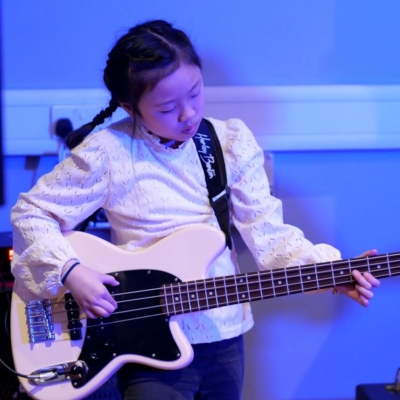 A young girl playing the bass guitar