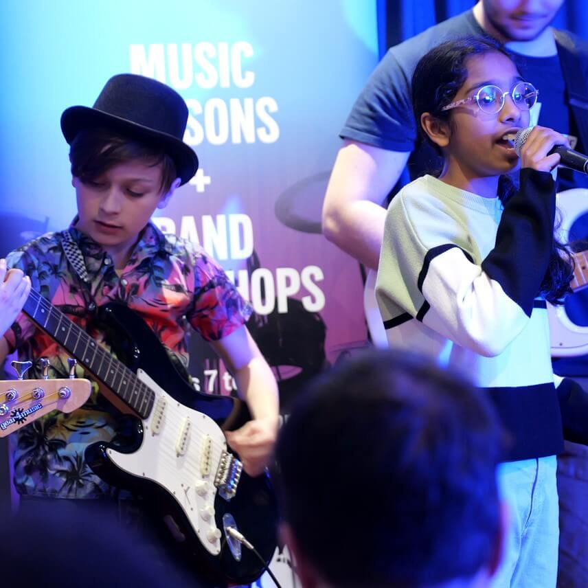 A young boy and girl playing guitar and singing at JAMM, Woking